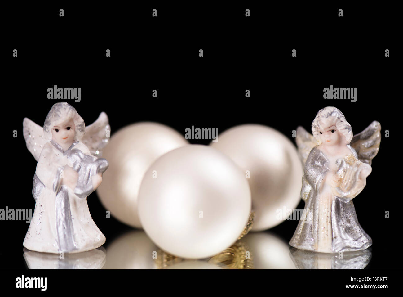 Drei dekorative Glaskugeln sind zwischen zwei dekorative Putten auf dem Glas als Weihnachts- und Silvester Dekoration in fron Stockfoto