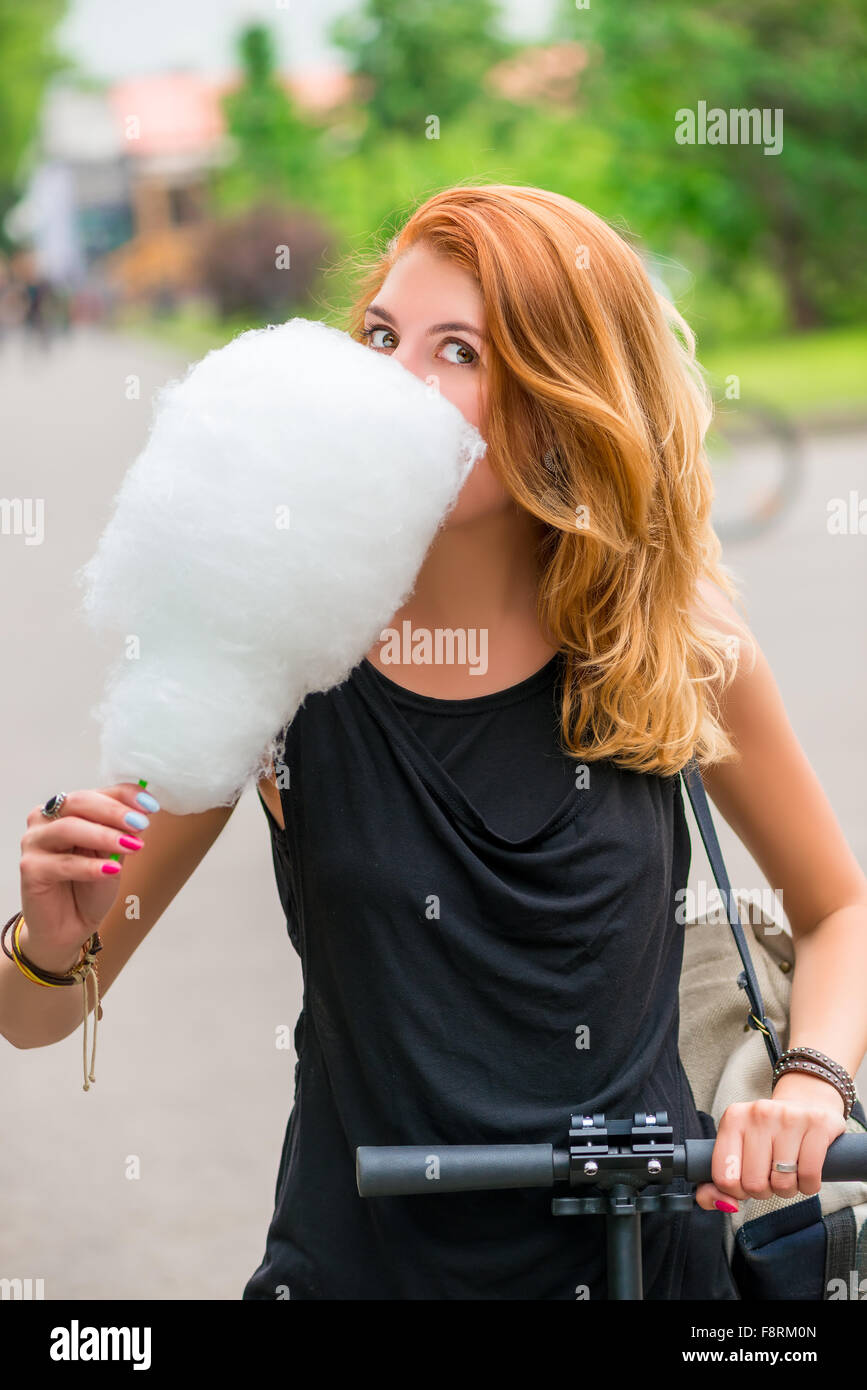 Mädchen 30 Jahre im Park spazieren und Zuckerwatte essen Stockfoto