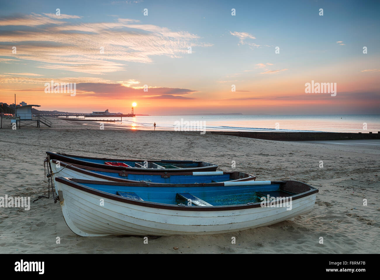 Atemberaubenden Sonnenaufgang Ove Rfishing Boote bei Durley Chine am Strand von Bournemouth in Dorset mit die Sonne über das Ende des Piers Stockfoto