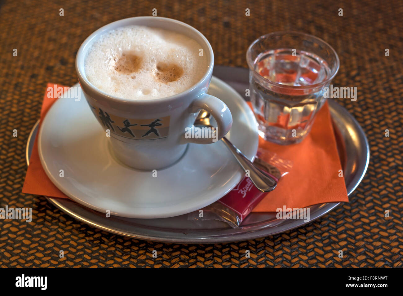 Cappuccino mit einem Glas Wasser auf einem Tablett Stockfoto