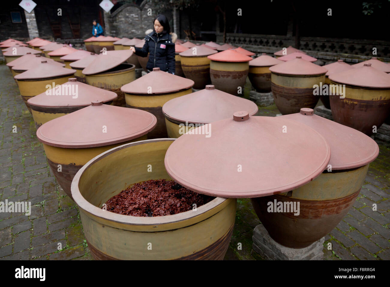 Ein Besucher erkundet die Tonkrügen mit Kunststoffdeckel Pixian Chili Bohnen letzten halten, während sie in einer Fabrik in Chengdu reift Stockfoto