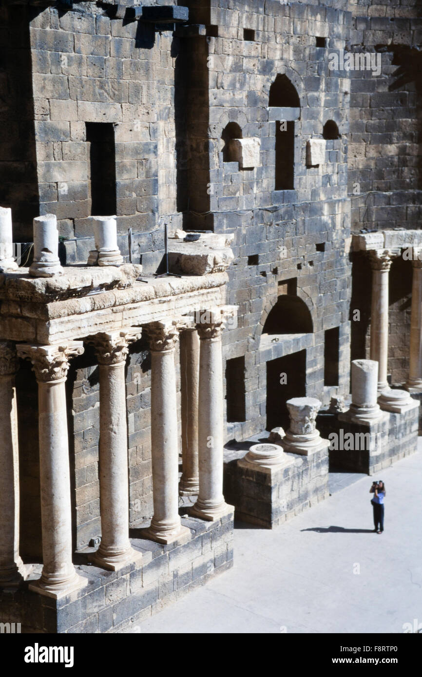 Ein weiblicher Touristen fotografiert im 2. Jahrhundert römische Theater in Bosra, Syrien. Wahrscheinlich unter Trajan errichtet, ist es das einzige Denkmal dieser Art mit seiner oberen Galerie in Form von einen überdachten Säulengang die integral erhalten geblieben ist. Es wurde zwischen 481 und 1231 befestigt. Stockfoto