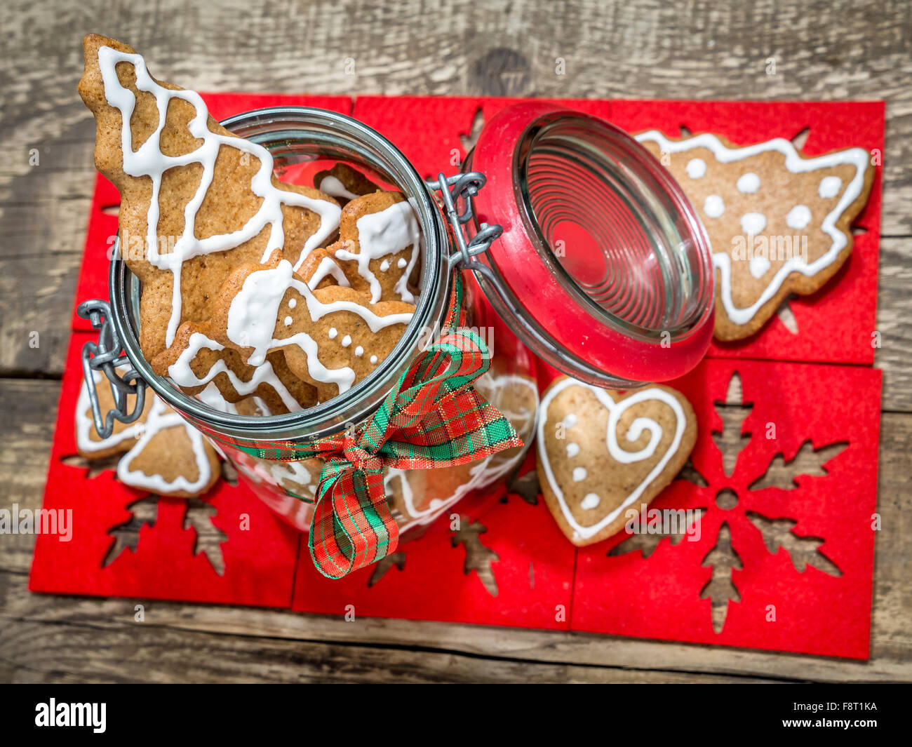 Sortierte Lebkuchen Weihnachtsplätzchen mit weißem Zuckerguss in Glas auf Tisch Stockfoto