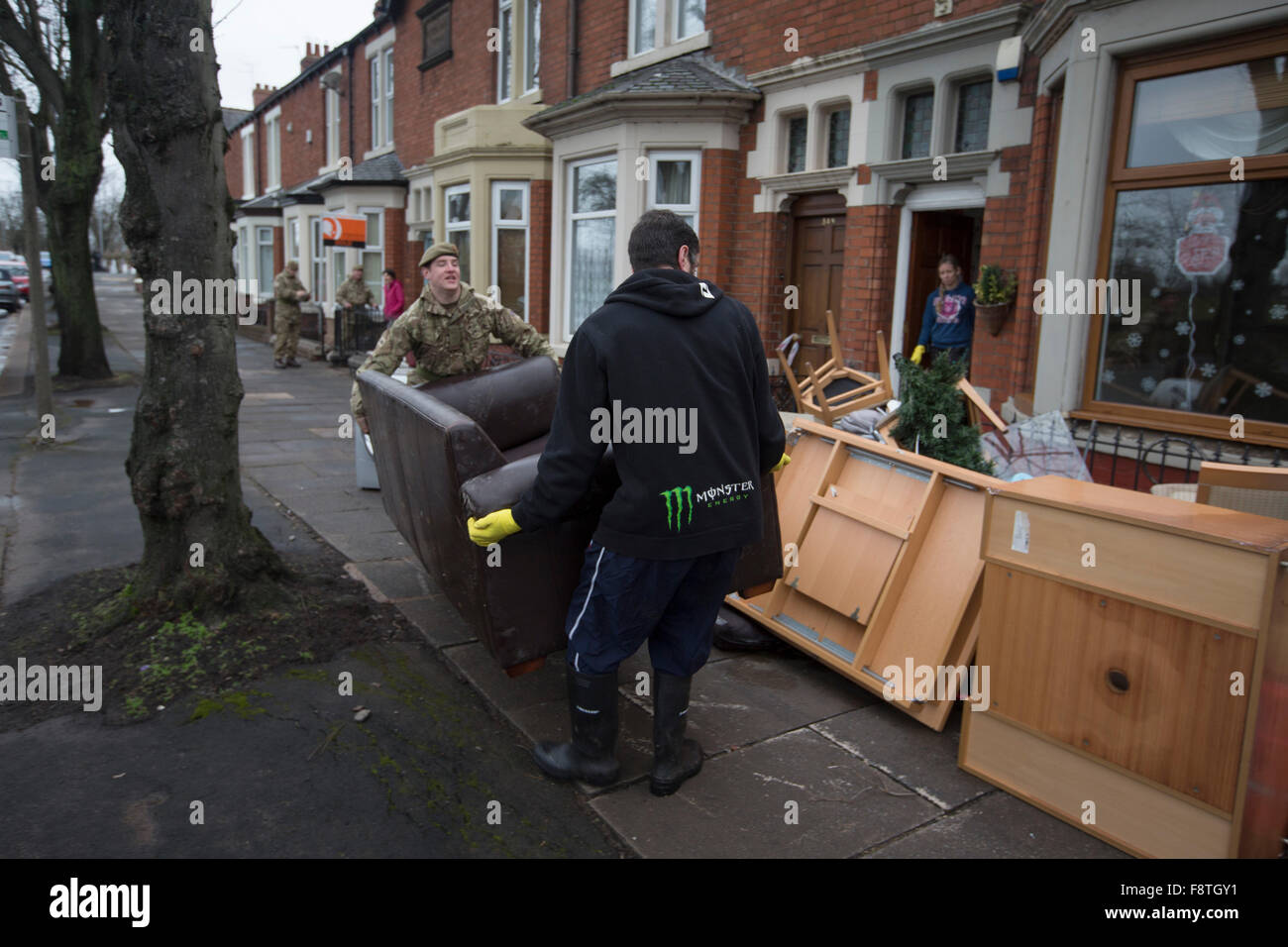 Ein Mitglied der Duke of Lancaster Regiment, mit Sitz in Preston, Lancashire, ein Bewohner von Warwick Road in Carlisle helfen entfernen Sie Möbel und andere Haushalte waren beschädigt durch Hochwasser am vergangenen Wochenende. Rekord Regen fallen in Cumbria verursacht Überschwemmungen auf mehrere Bereiche von Carlisle, wodurch Häuser durch Rettungsdienste evakuiert werden. Stockfoto