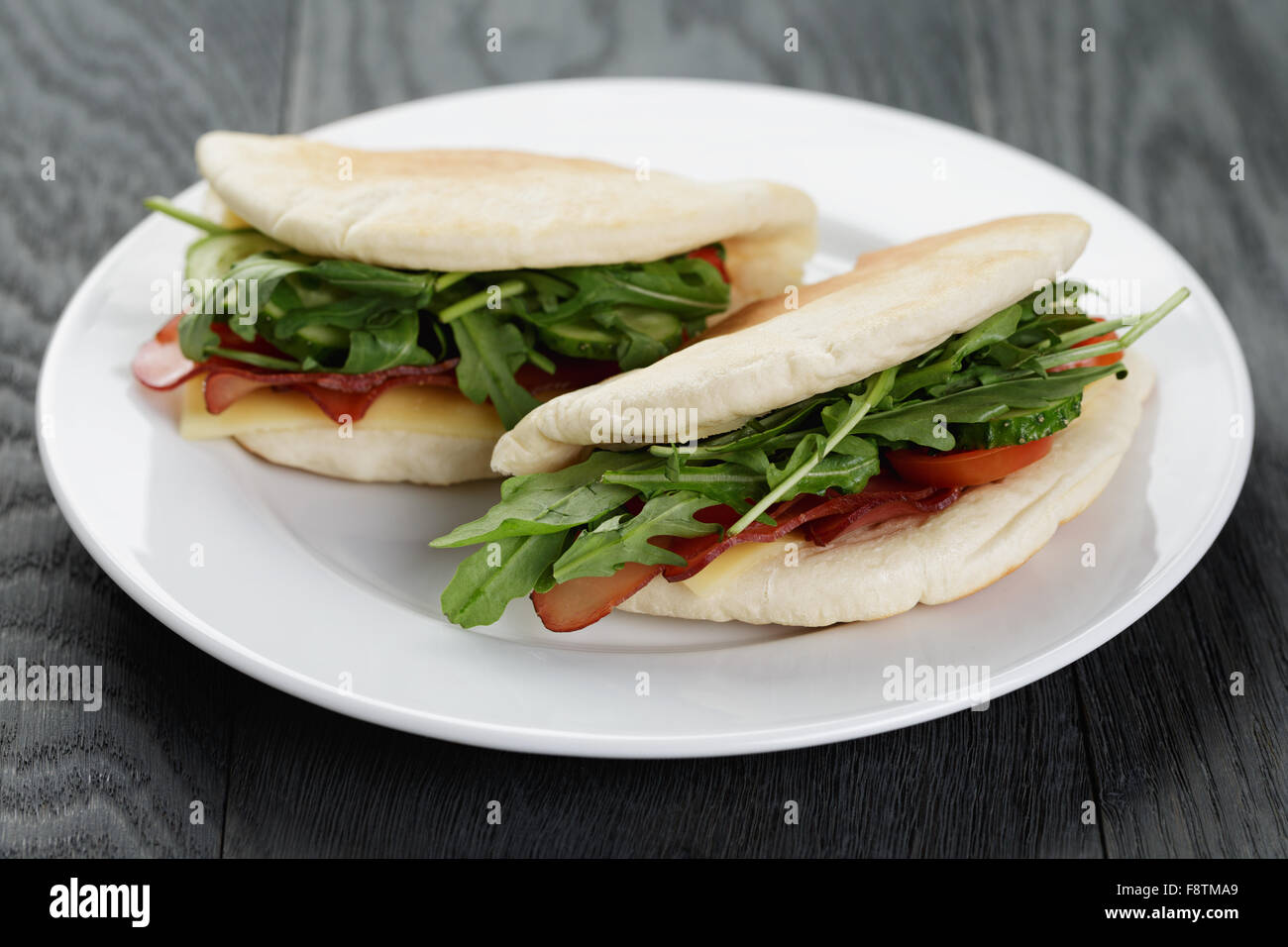 rustikale Sandwiches mit Schinken, Rucola und Tomaten im Fladenbrot Stockfoto