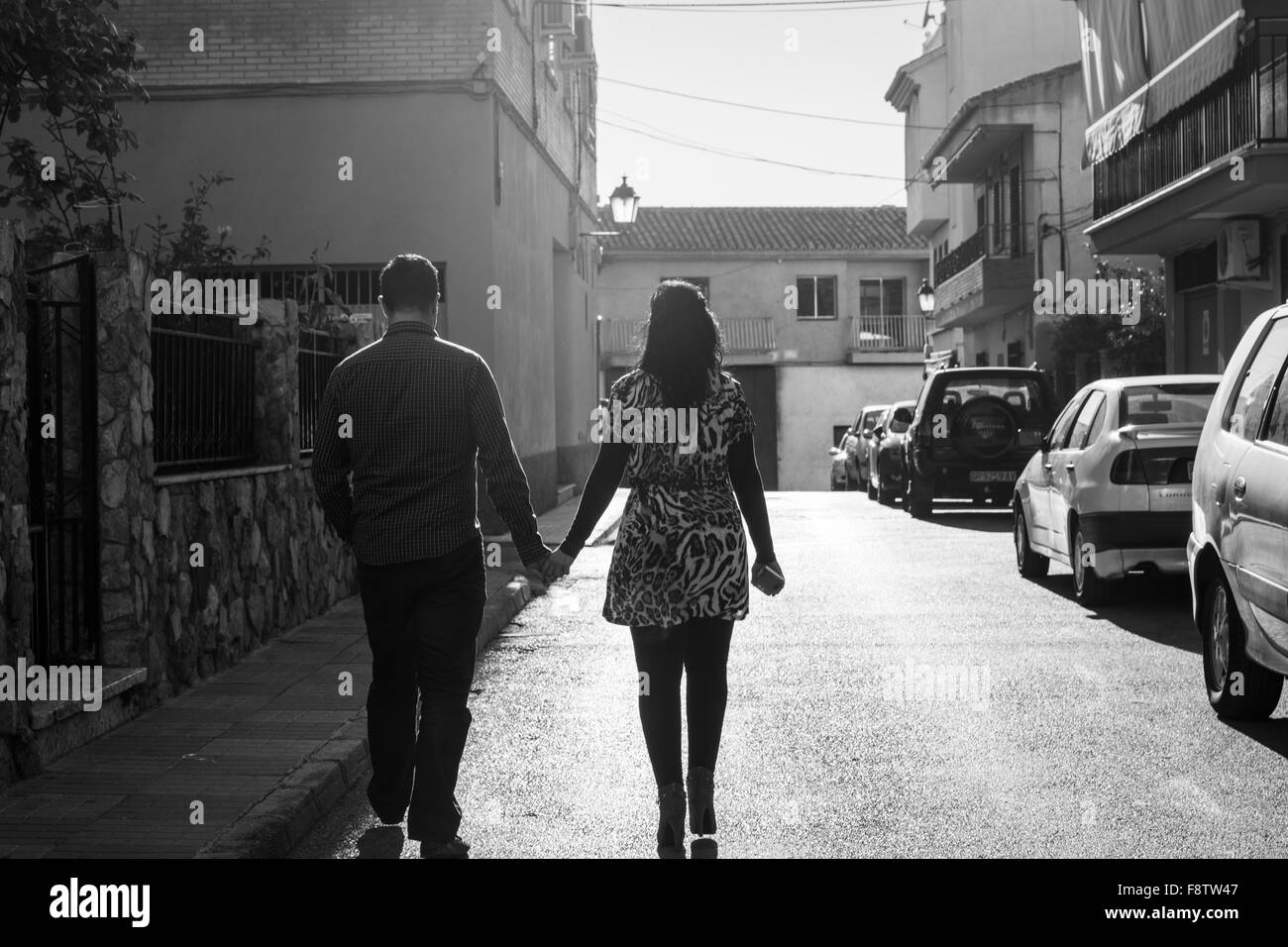 Ein junges Paar auf der Straße Hand in Hand mit dem Rücken zur Kamera. Sehr romantische und atmosphärische. Monochrom. Stockfoto