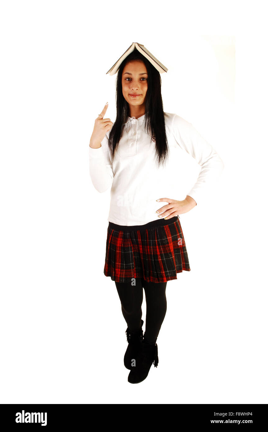 Ein schönes junges Mädchen in Schuluniform mit einem Buch auf ihrem Kopf stehen für weißen Hintergrund mit ihren langen schwarzen hai Stockfoto