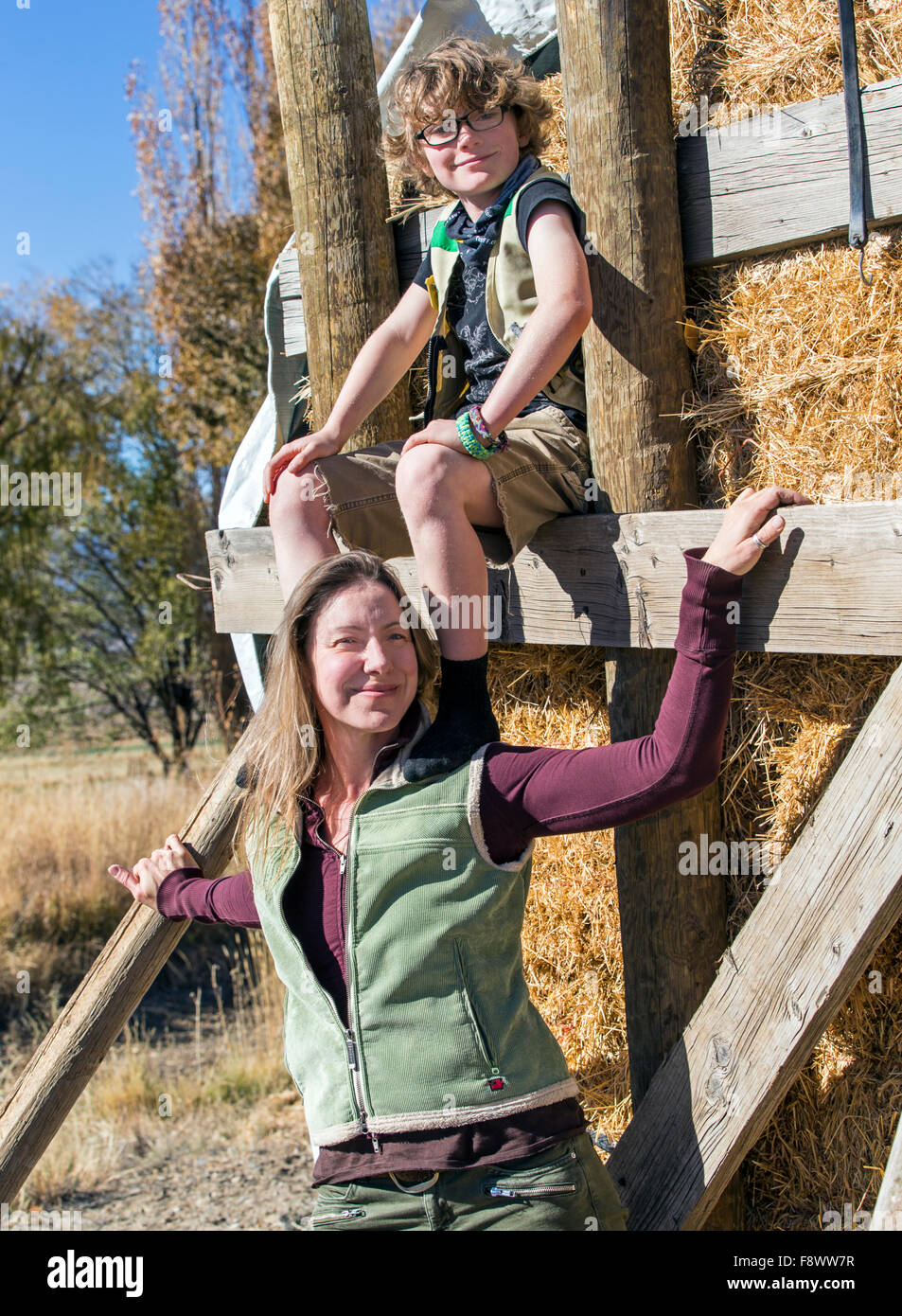 Attraktive Mutter und seinem kleinen Sohn posieren für Fotos von gestapelten Heuballen auf ranch Stockfoto