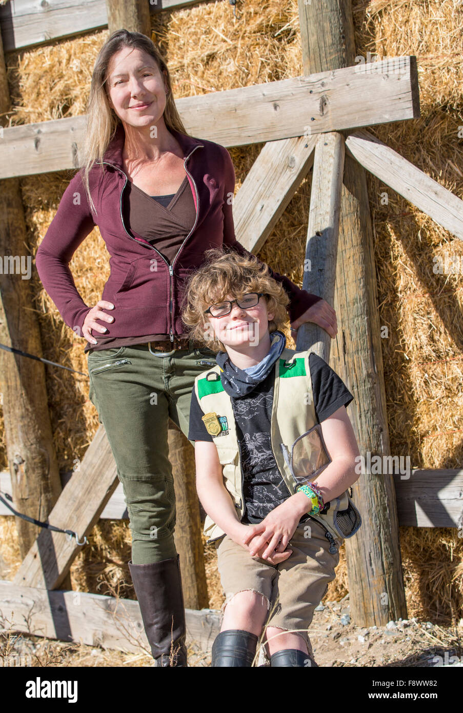 Attraktive Mutter und seinem kleinen Sohn posieren für Fotos von gestapelten Heuballen auf ranch Stockfoto