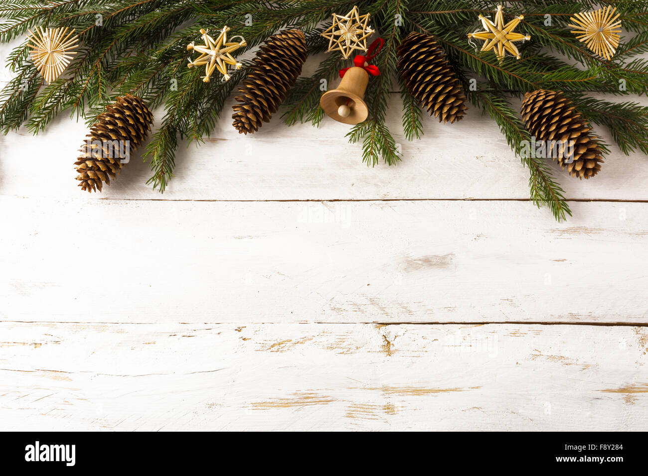 Hintergrund Dekoration Tanne Äste, Stroh Weihnachtsschmuck, hölzerne Jingle Bell, Tannenzapfen auf Whiteboards, Tiefenschärfe, c Stockfoto