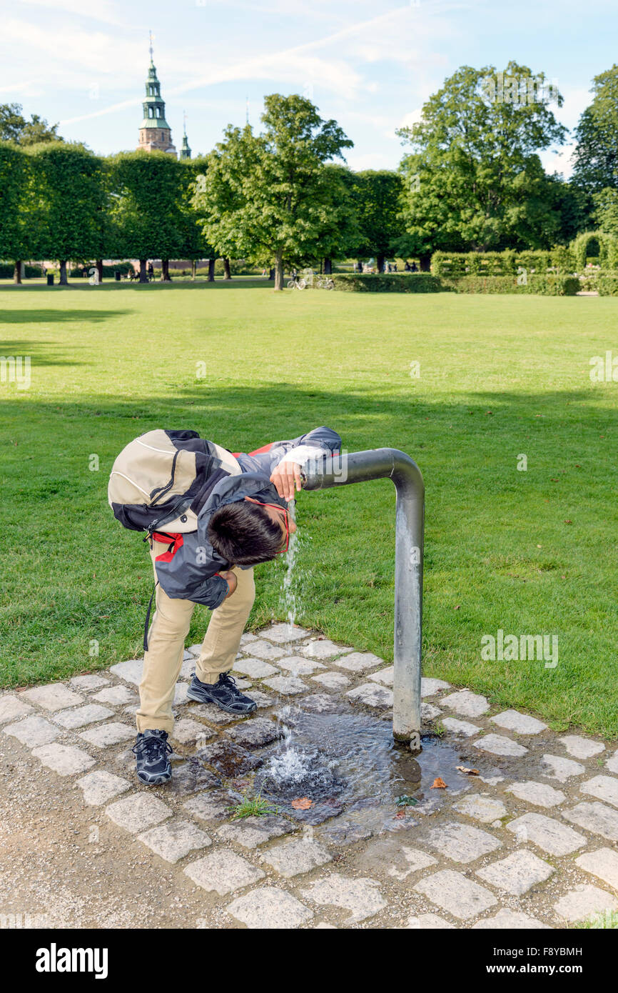 Junge immer einen wohlverdienten Drink aus einem Brunnen in einem Park. Stockfoto