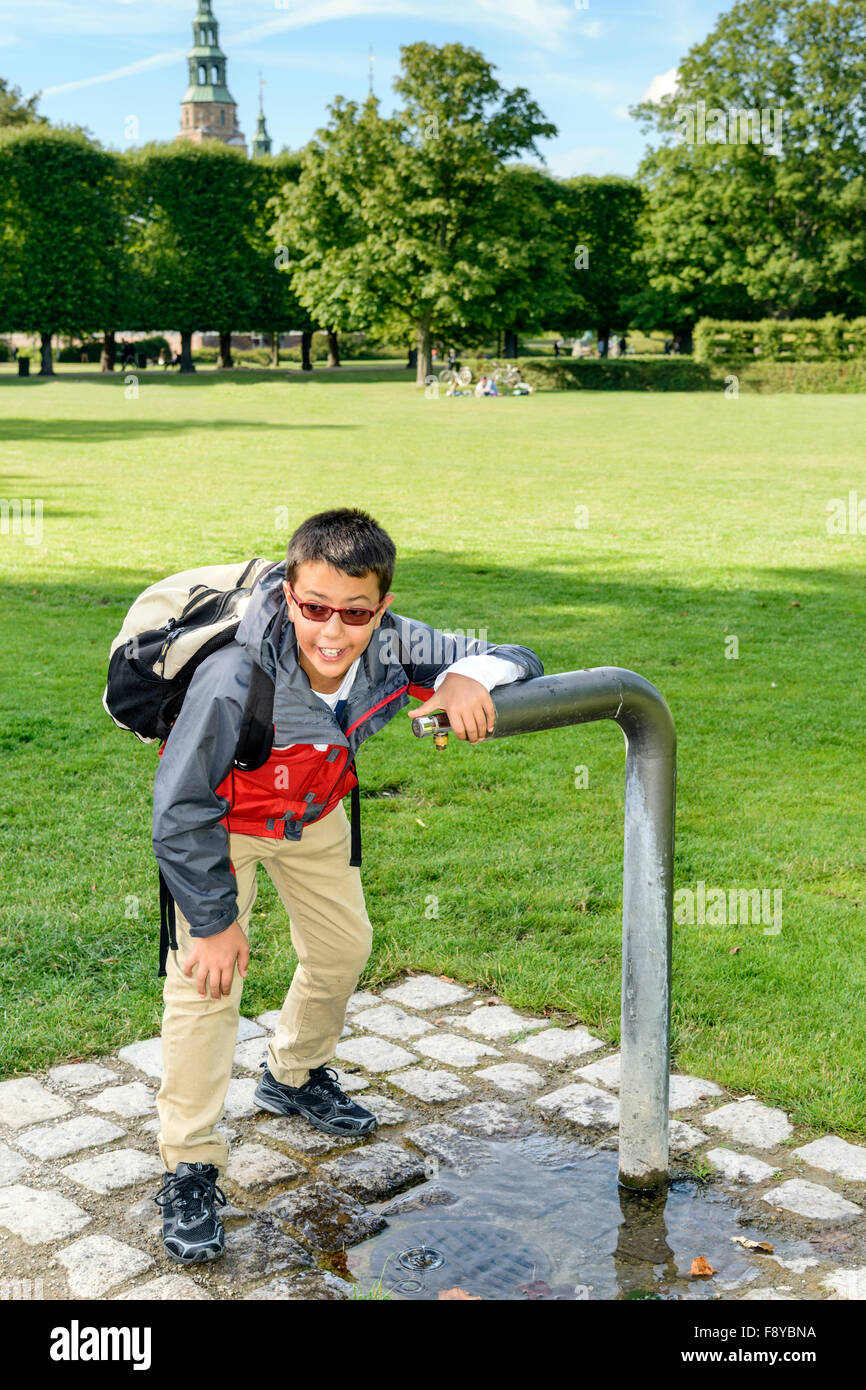 Junge immer einen wohlverdienten Drink aus einem Brunnen in einem Park. Stockfoto