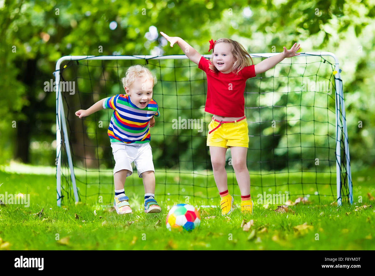 Zwei glückliche Kinder spielen Fußball im Freien im Schulhof. Kinder spielen Fußball. Aktiv Sport für Vorschulkind. Stockfoto