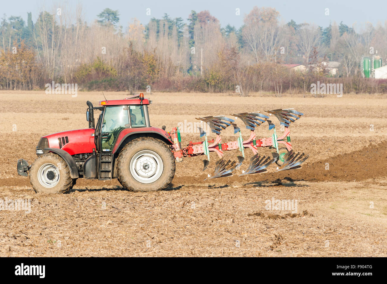Landwirtschaftliche Arbeit, roter Traktor ein Feld pflügen Stockfoto
