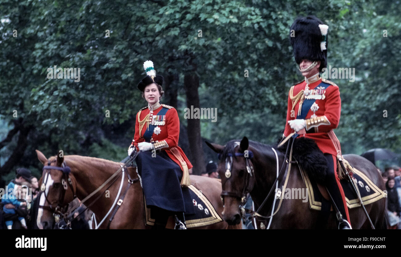 Eine junge Königin Elizabeth II. Und Prinz Philip reiten ihre Pferde vom Buckingham Palace entlang der Straße im Juni 1963 bis zur Trooping the Color Ceremony in London, England. Dieses jährliche britische königliche Ereignis markiert auch den offiziellen Geburtstag der Königin und wird gemeinhin als die Queen's Birthday Parade; sie war 37 Jahre alt zu der Zeit dieses Foto aufgenommen wurde. Seit 1987 reist die Königin in einer Kutsche statt zu Pferd zur Zeremonie. Historisches Foto. Copyright Michele & Tom Grimm. Stockfoto
