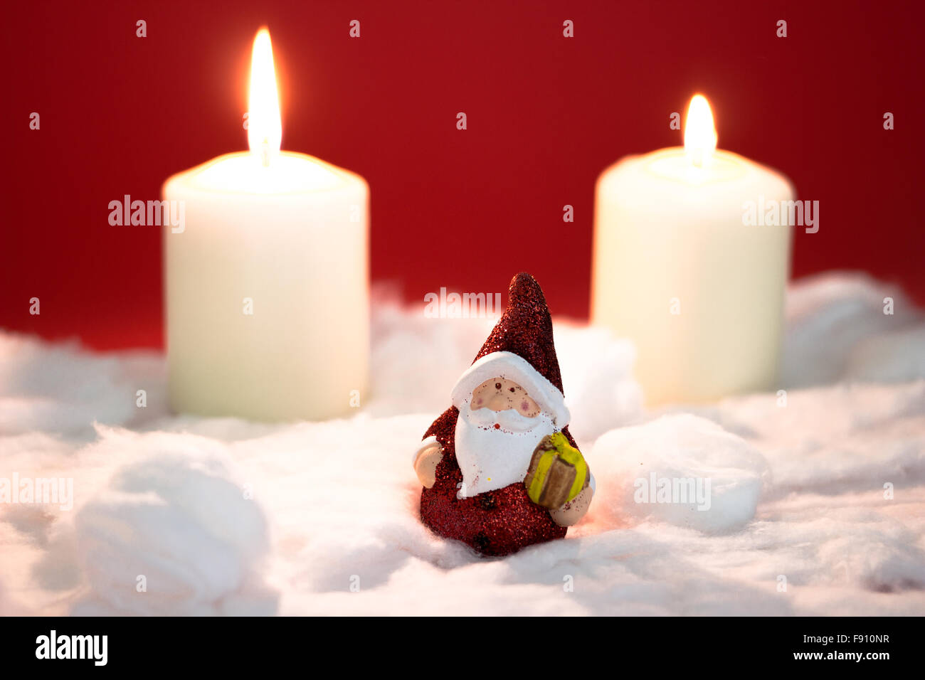 Santa Claus mit brennenden Kerzen auf rotem Grund Stockfoto