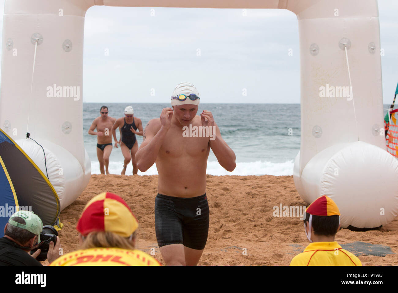 Sydney, Australien. 13. Dezember 2015. Schwimmer an der Ziellinie des Bilgola Beach Ocean Swimming Race über 1,5 Kilometer, Teil der jährlichen Pittwater Ocean Swim Serie, Sydney, Australien. Der männliche Schwimmer überquert die Ziellinie. Kredit: model10/Alamy Live News Stockfoto