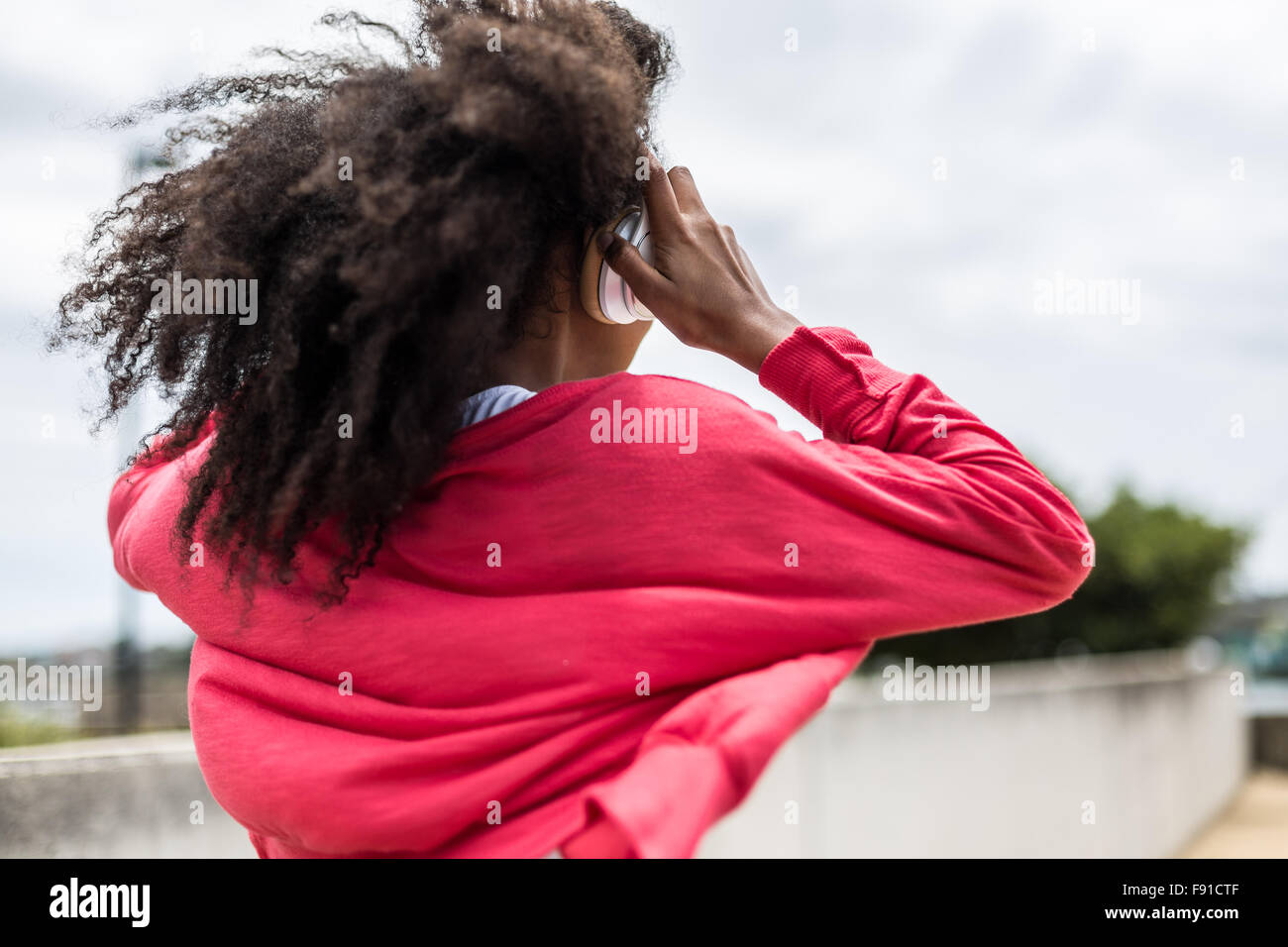 Eine junge Mischenrennen Frau anhören von Musik auf einem Smartphone mit Kopfhörern im freien Stockfoto