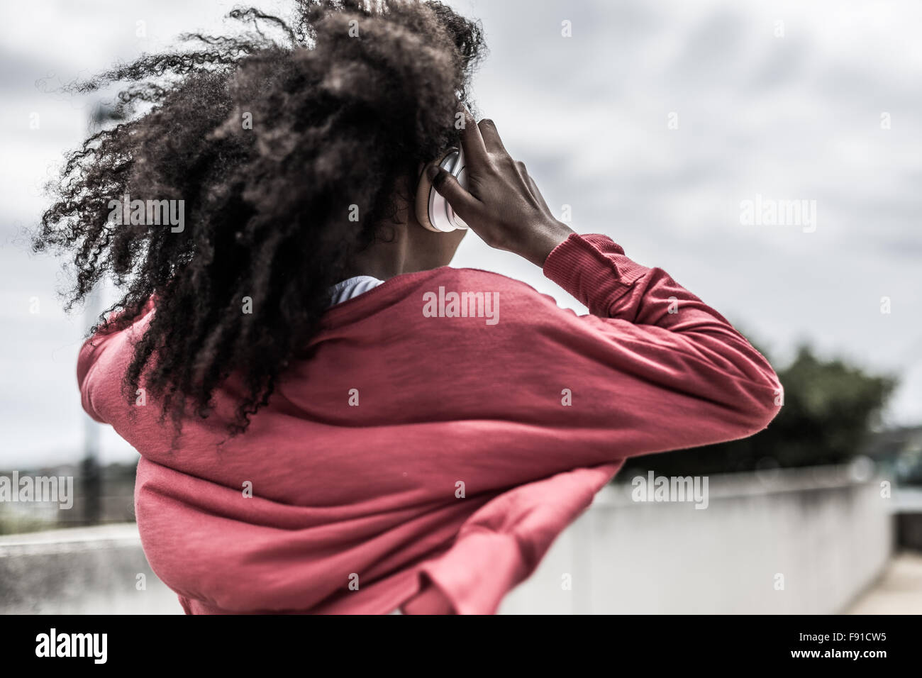 Eine junge Mischenrennen Frau anhören von Musik auf einem Smartphone mit Kopfhörern im freien Stockfoto