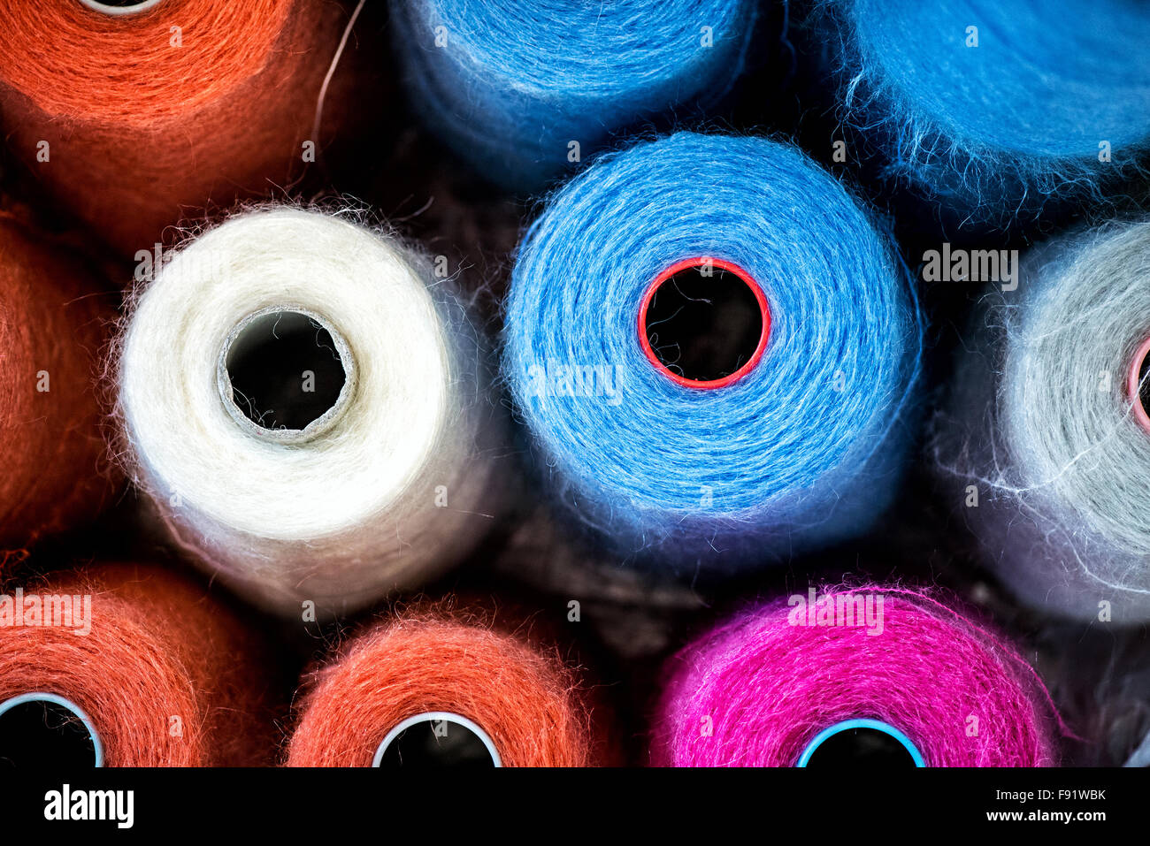 Bunte Walzen oder Spulen der Baumwollfaden für verwenden in der Strickwaren und Bekleidungsindustrie von oben gesehen, voll Rahmenhintergrund Stockfoto