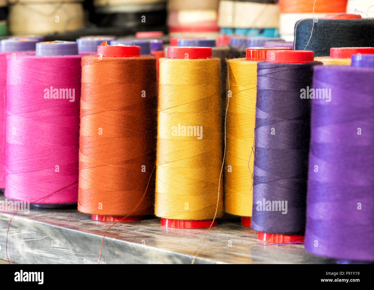 Textil-Still-Leben - in der Nähe von industriellen Größe Spulen von Baumwollgarn in leuchtenden Farben von Rosa, Orange, gelb und lila Stockfoto