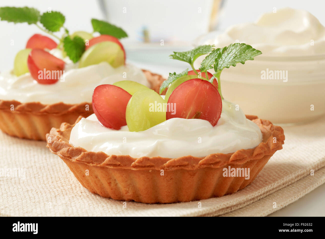 Kleine Creme Törtchen garniert mit frischen Weintrauben Stockfoto
