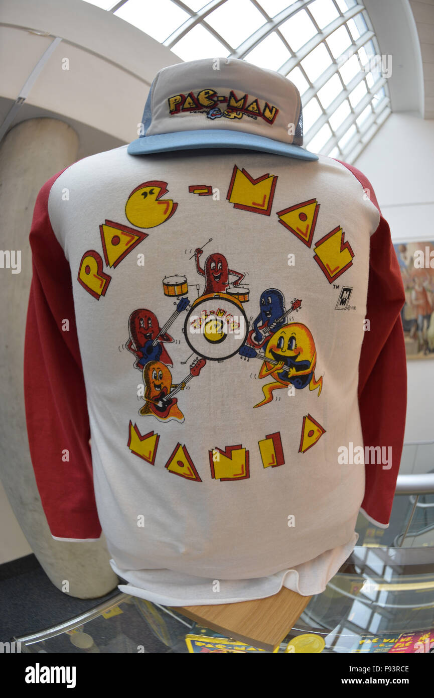 Garden City, New York, USA. 12. Dezember 2015. Ein Vintage Pac-Man-Mania-bunte Baseball-Shirt und Cap aus den 1980er Jahren sind auf dem Display mit andere Arcade-Erinnerungsstücke während Öffnung Tag der Arcade-Alter Ausstellung, wo die Besucher authentische klassische Spiele im Arcade in Long Island im Cradle erleben of Aviation Museum eingerichtet. Auf Hemd spielen Pac-Man-Charaktere Musikinstrumente. Ausstellung läuft vom 12. Dezember 2015 durch 3. April 2016. © Ann Parry/ZUMA Draht/Alamy Live-Nachrichten Stockfoto