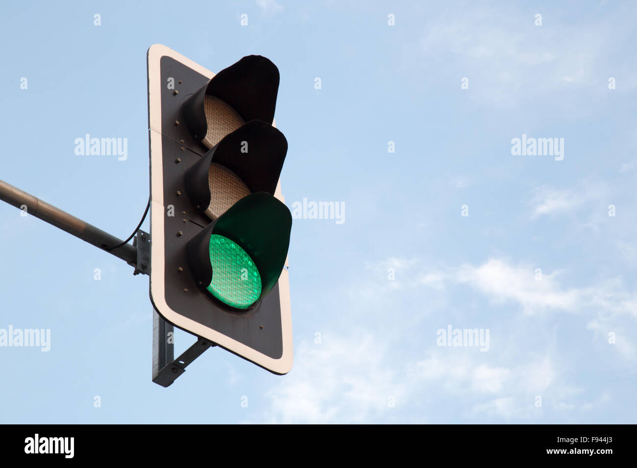 Grüne Ampel und blauer Himmel mit weißen Wolken Stockfoto