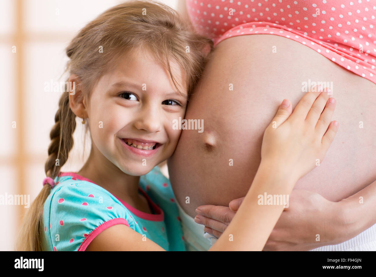 Eine glückliche Familie. Kind Mädchen umarmt Bauch der schwangeren Mutter Stockfoto