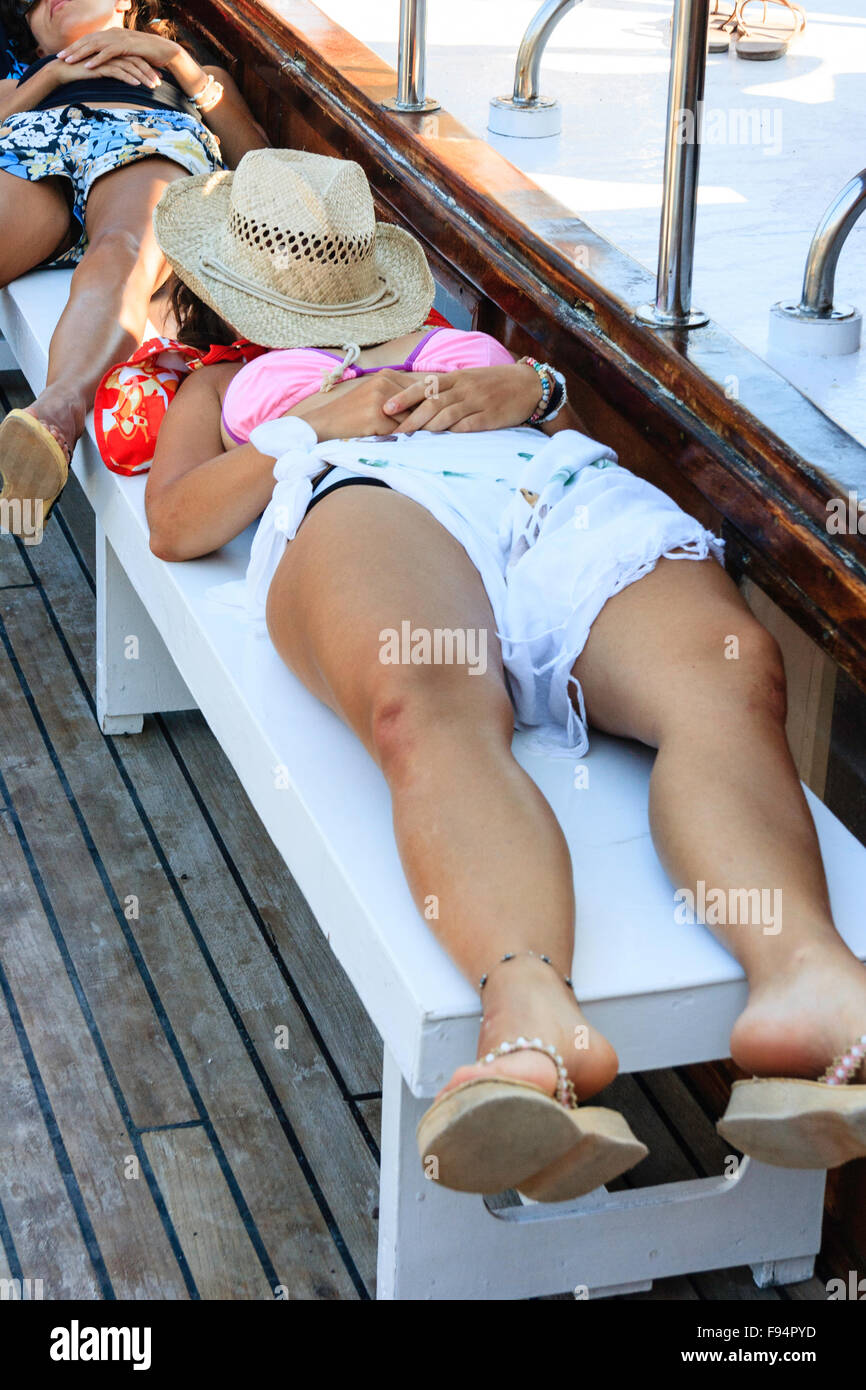 Kykladen, Santorin, Thira. Junge Frau im Bikini, Festlegung auf der Werkbank an Deck Exkursion Boot, schlafend, mit Strohhut für Gesicht. Stockfoto Kykladen, Santorin, Thira. Junge Frau im Bikini, Festlegung auf der Werkbank an Deck Exkursion Boot, schlafend, mit Strohhut für Gesicht. Stockfoto