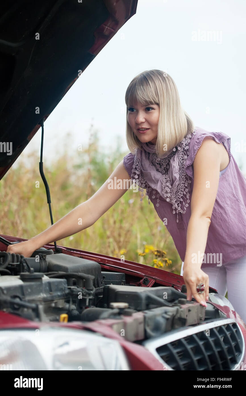 Junge Frau, die unter der Motorhaube Stockfoto