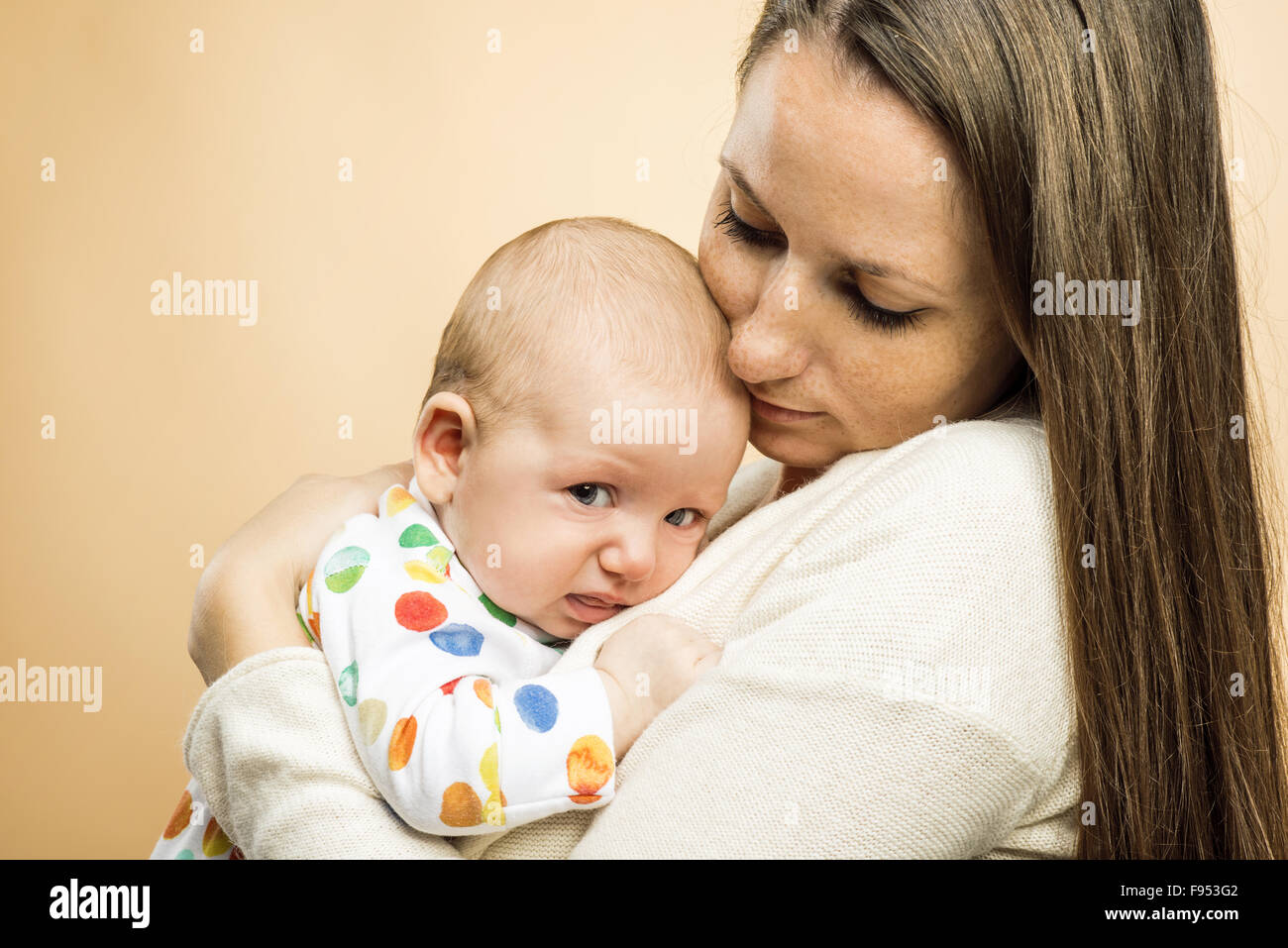 Weinendes Kind mit Mutter Studio gedreht auf Beige Hintergrund Stockfoto