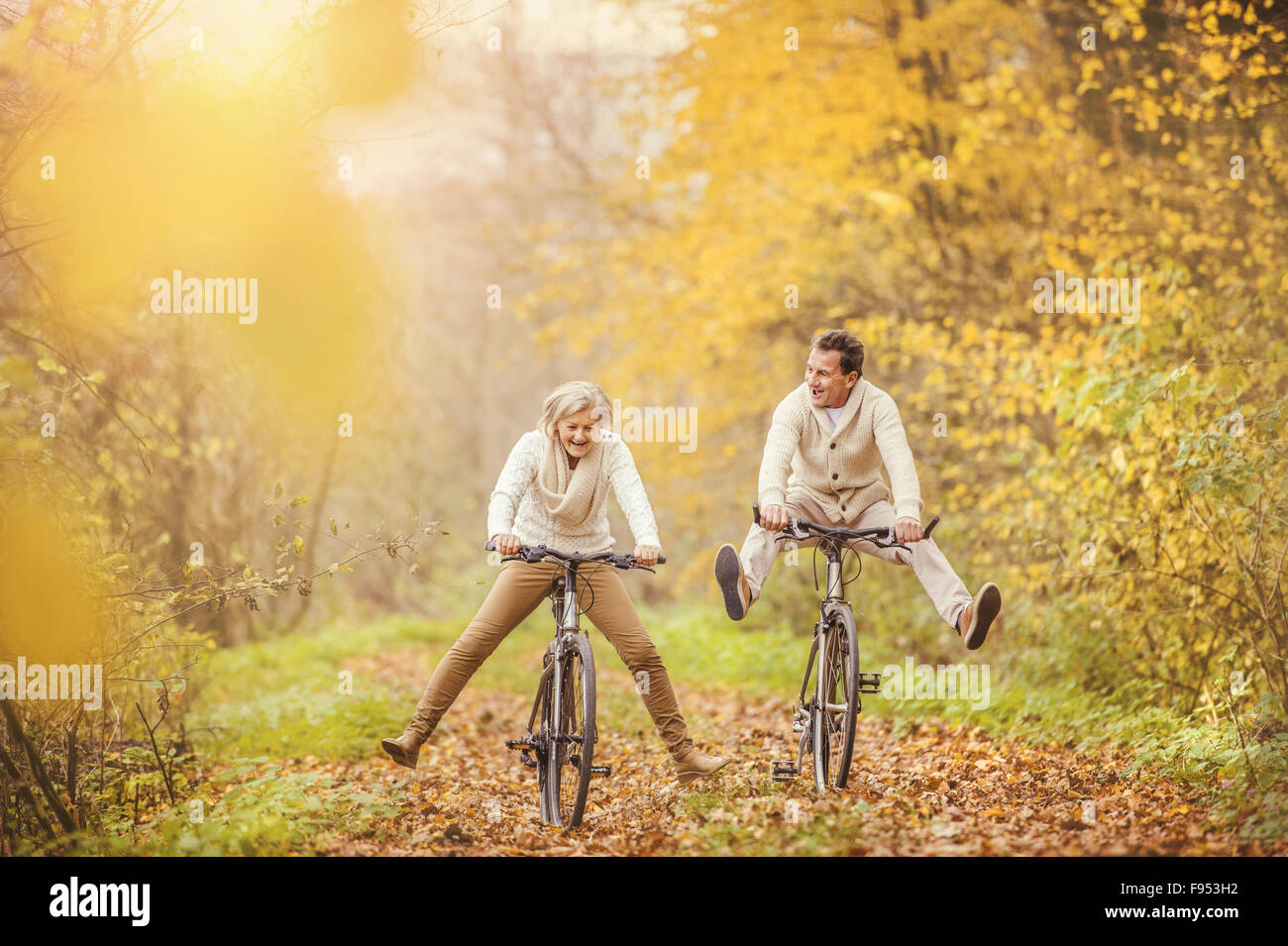 Aktive Senioren mit Fahrrad in der herbstlichen Natur. Sie haben Spaß im Freien. Stockfoto