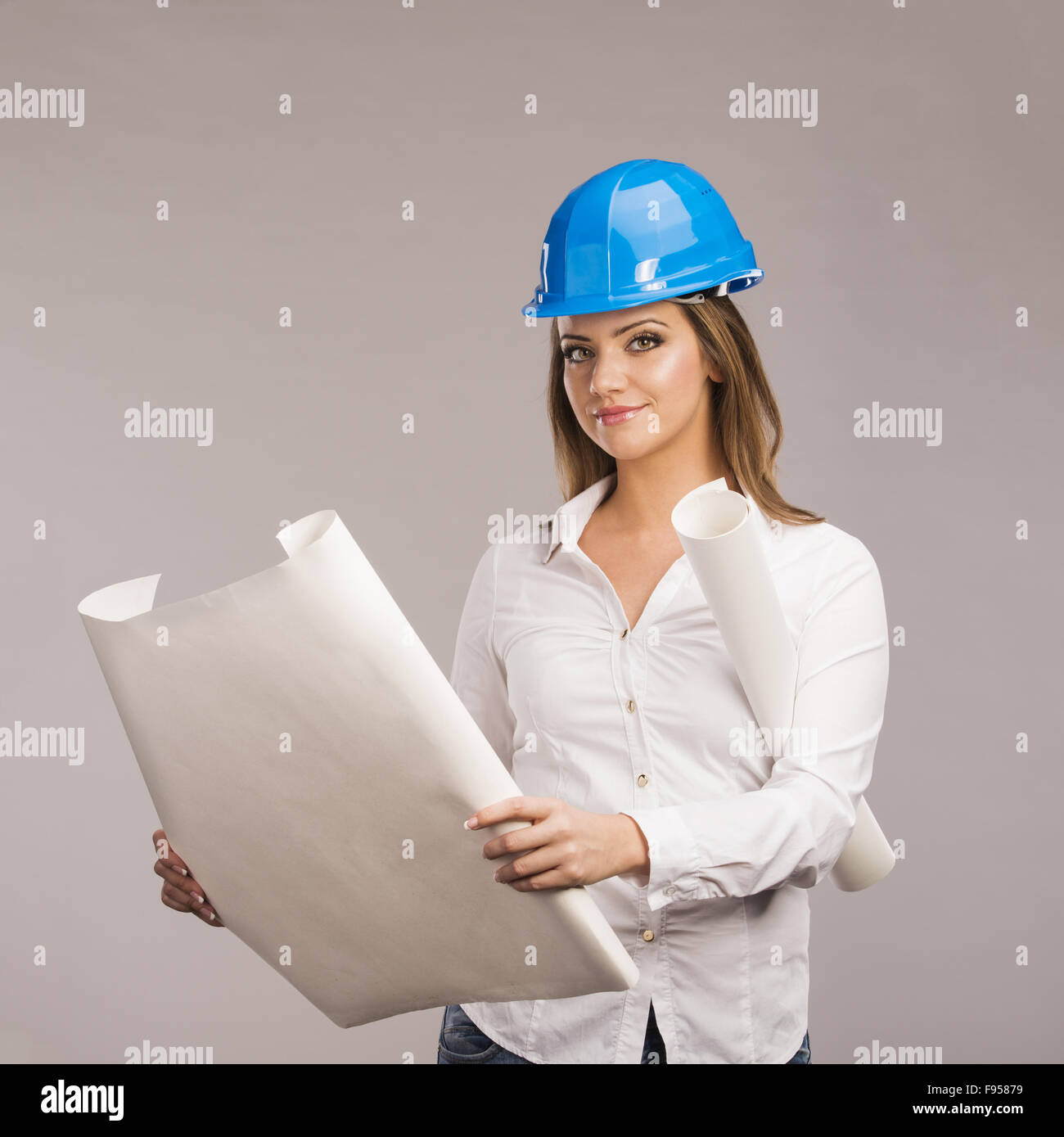 Porträt der jungen Frau Architekt mit blauen Schutzhelm und Papierpläne, isoliert auf weißem Hintergrund Stockfoto