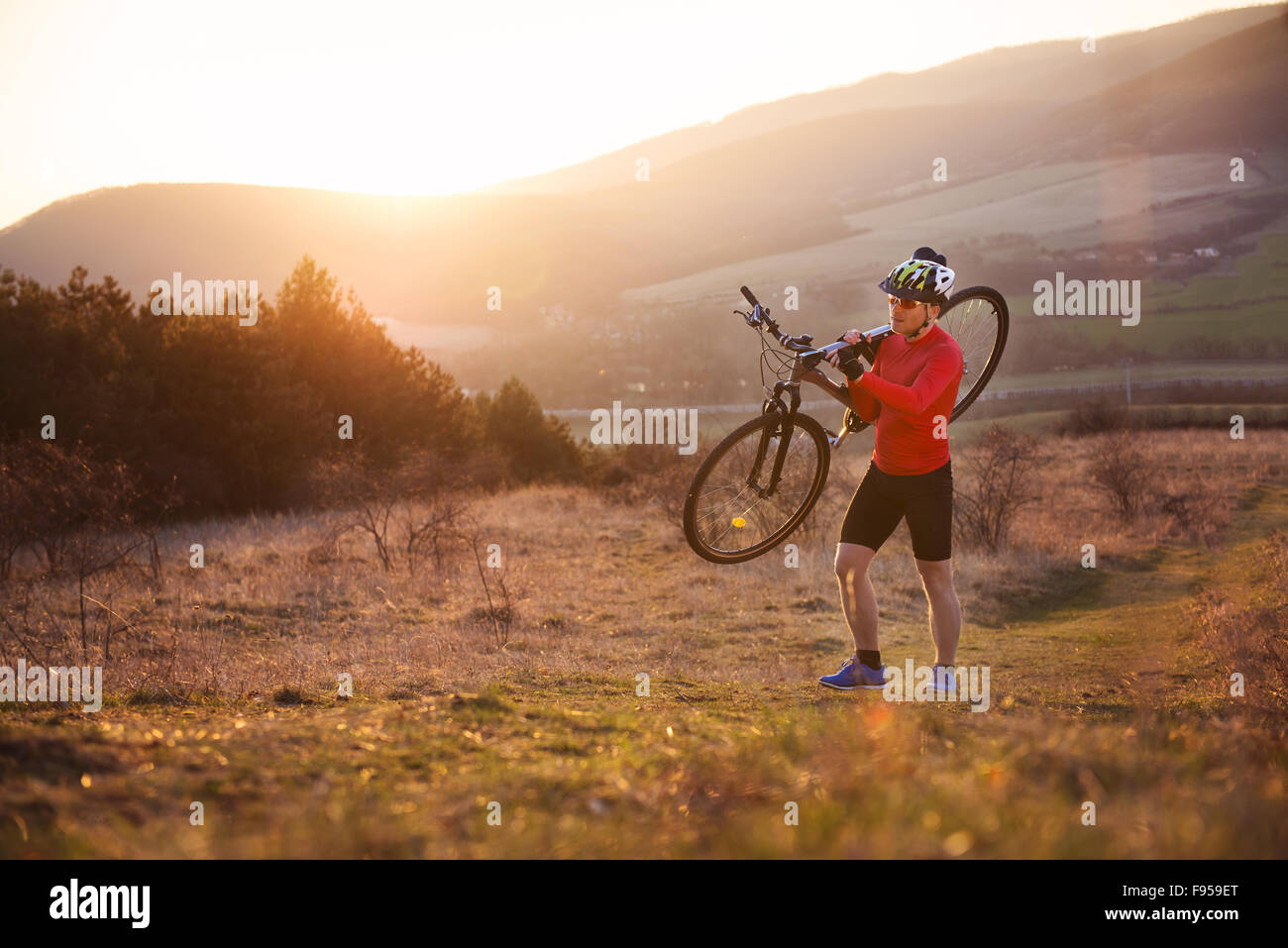 Radfahrer-Mann mit seinem Mountainbike auf einer sonnigen Wiese Stockfoto