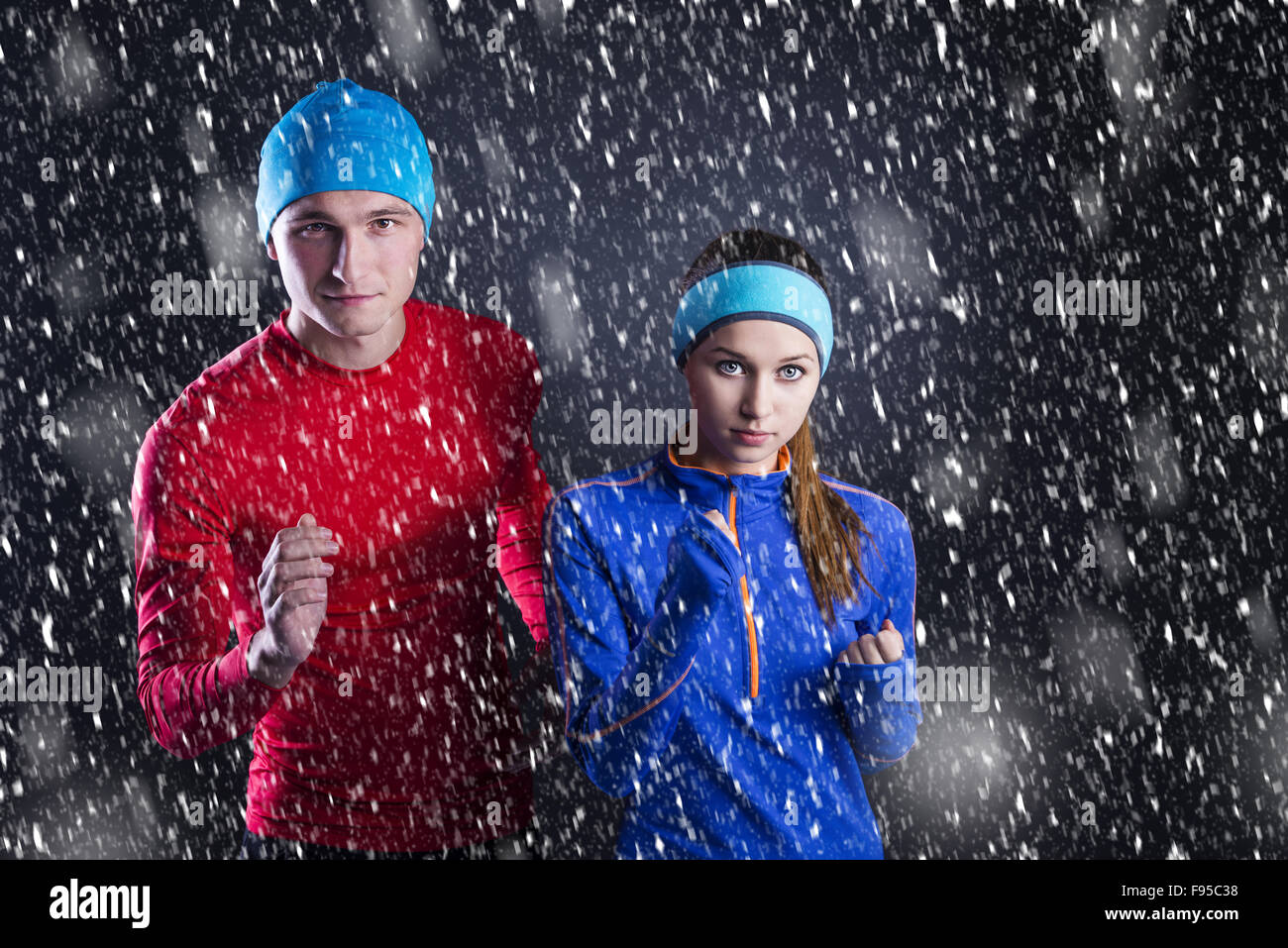 Junge Fitness-Sportler stehen draußen im kalten Winternacht. Schnee fällt um. Stockfoto
