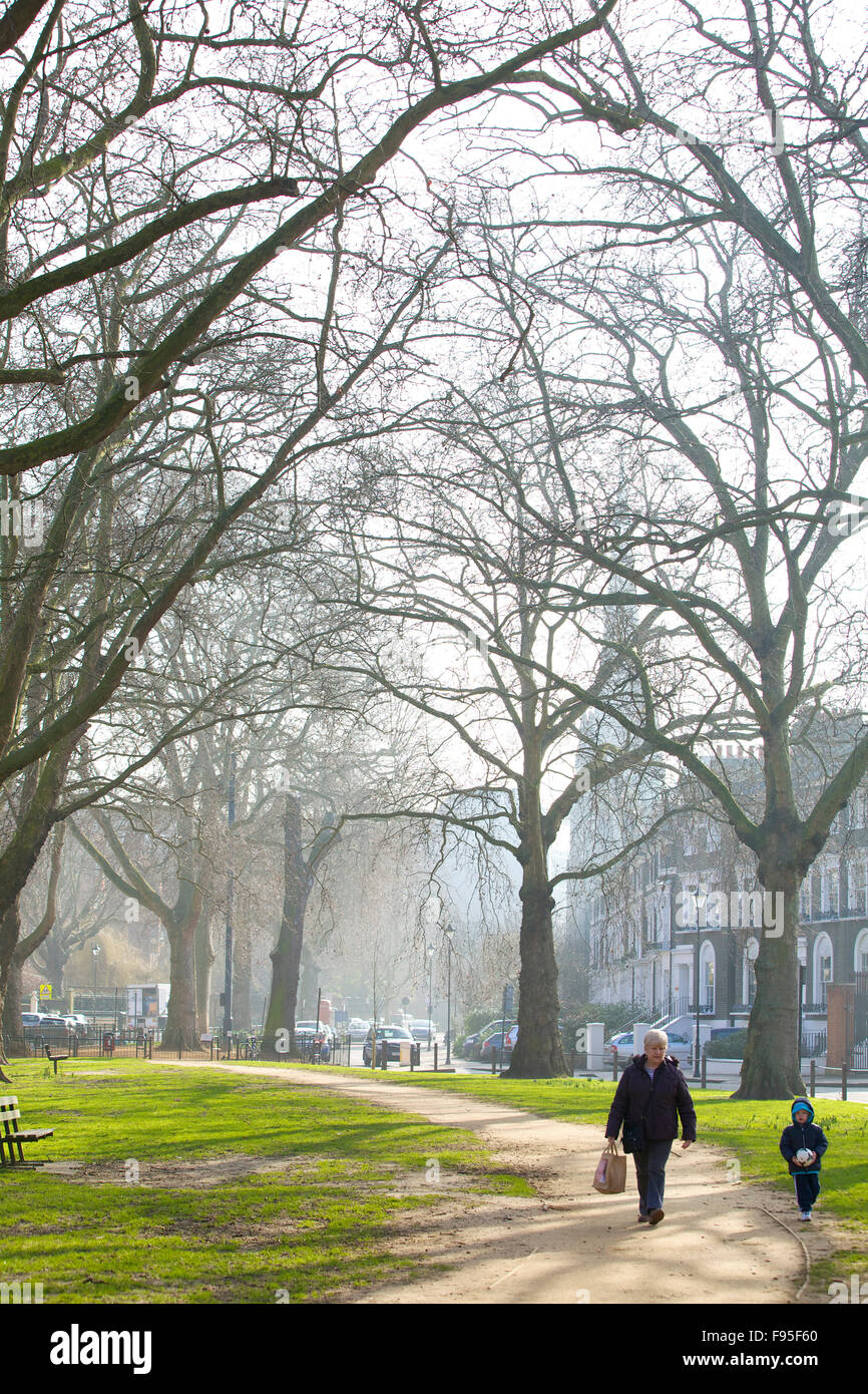 Hammersmith, London. Grünfläche oder einen Park in Hammersmith. Von Bäumen gesäumten Weg. Ein Erwachsener und Kind zu Fuß auf den Weg. Stockfoto