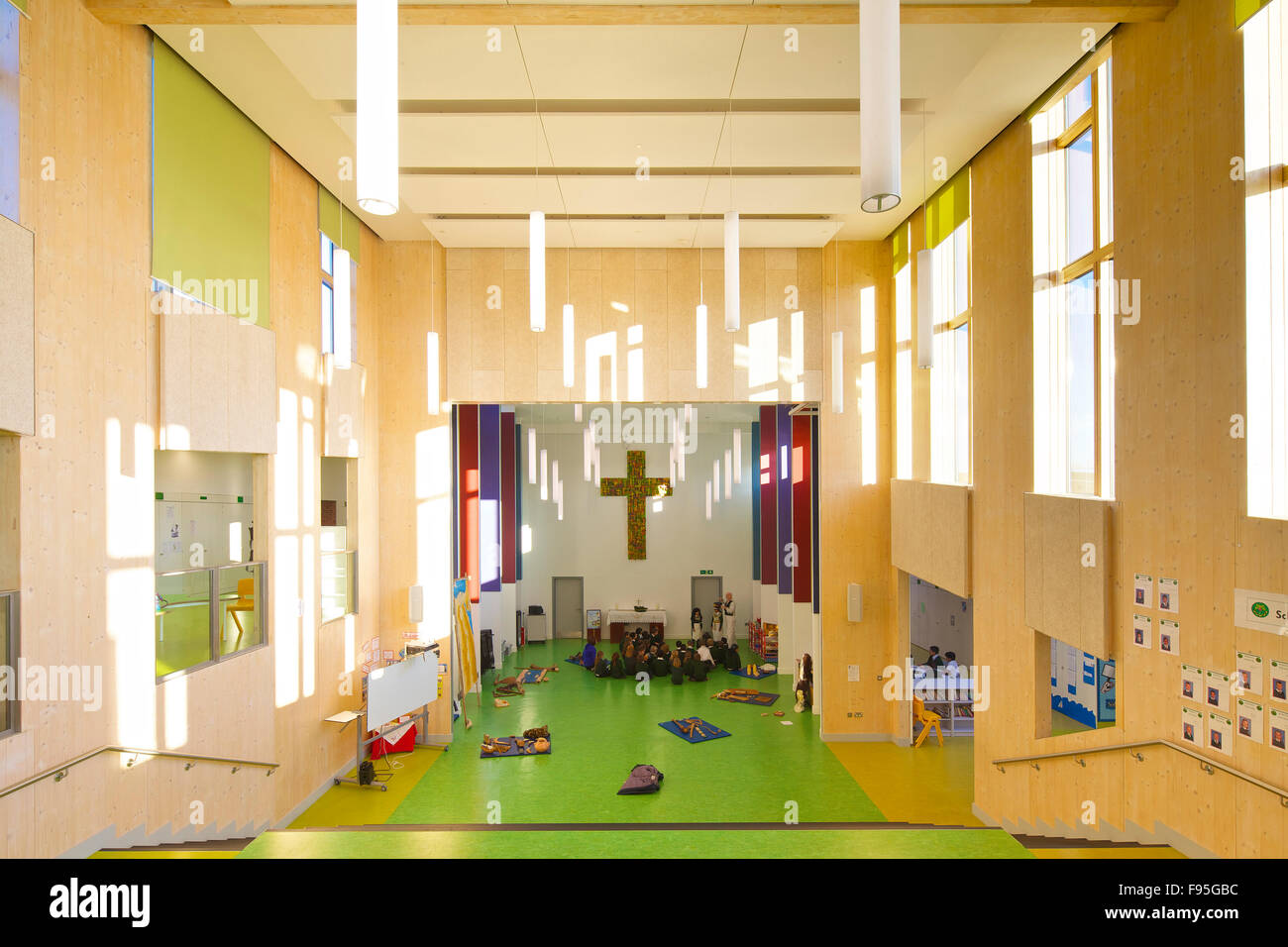 St.-Peter katholische Grundschule, Gloucester. Innenansicht einer Halle mit Studenten in einem Kreis in katholischen Grundschule St. Peter. Großes Kruzifix an der Wand hängen. Stockfoto