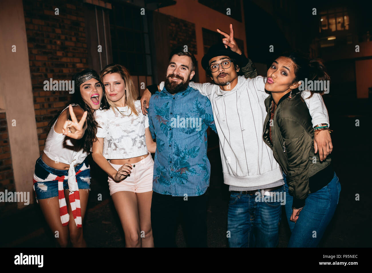 Gemischtrassigen Gruppe von jungen Leuten eine Party. Junge Männer und Frauen posieren für die Kamera mit Victory-Zeichen. Stockfoto