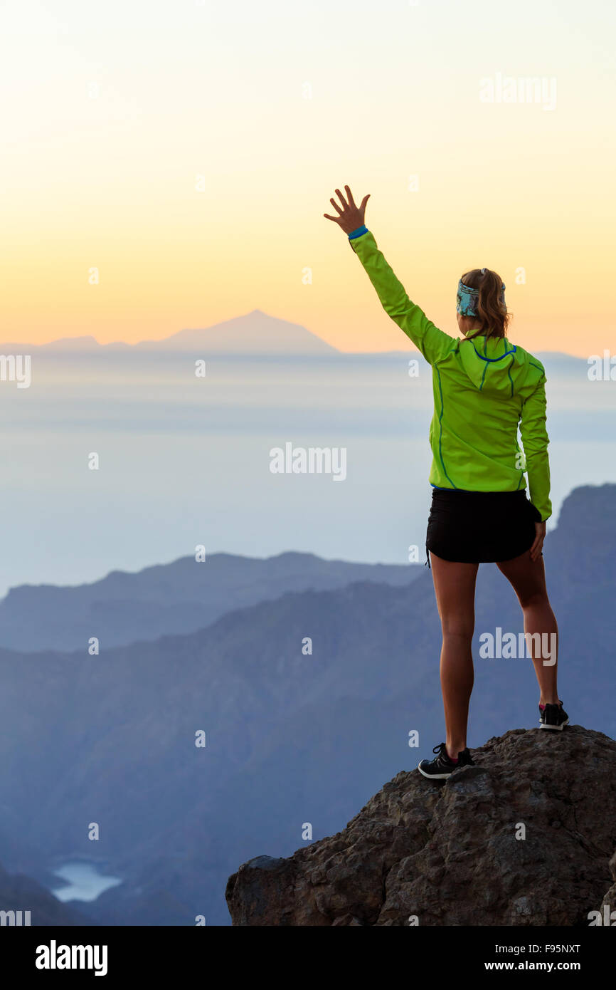 Frau erfolgreich Wandern, Klettern im Gebirge, Motivation und Inspiration im wunderschönen Sonnenuntergang und das Meer. Weibliche Wanderer mit Armen Stockfoto