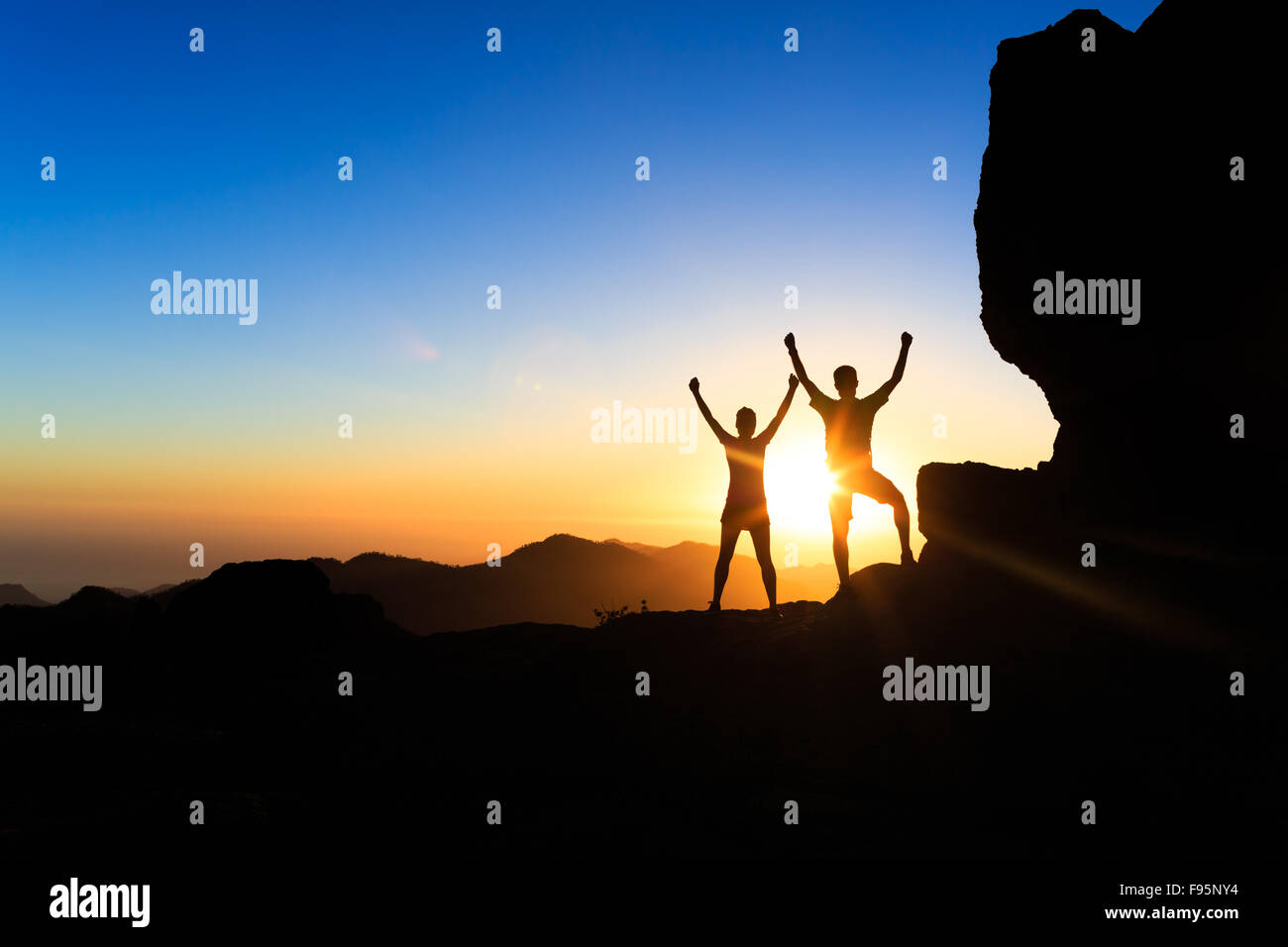 Teamarbeit paar Wanderer Erfolg im Sonnenuntergang Gebirge, erreichen mit ausgestreckten Armen. Junger Mann und Frau auf felsigen Berg Stockfoto
