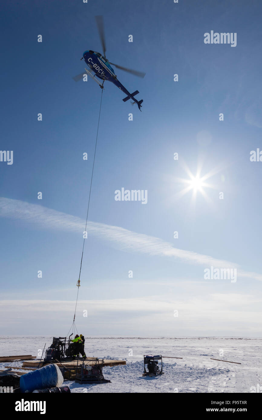 A helicopter positions part of an exploration drill on a platform near Lac de Gras, Northwest Territories, Canada. Stockfoto