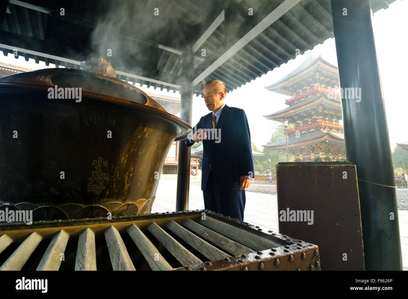 Ein Geschäftsmann hält inne, atmen Sie wohltuende Dämpfe im Shinshoji Tempel in Narita, Japan Stockfoto