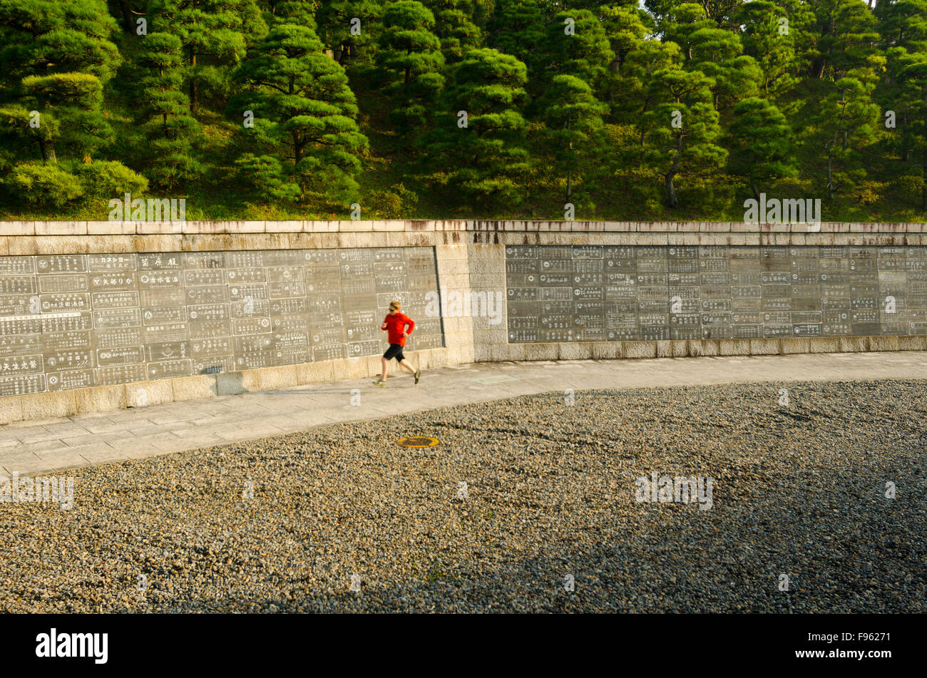 Eine Frau joggt vor einer Wand voller japanischen Schrift im Shinshoji Tempel in Narita, Japan Stockfoto