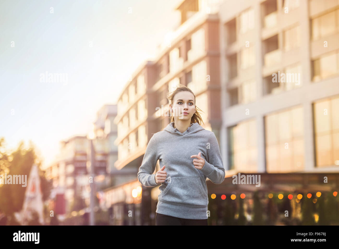 Junge weibliche Läufer in hoody ist in der Stadtstraße Joggen. Stockfoto