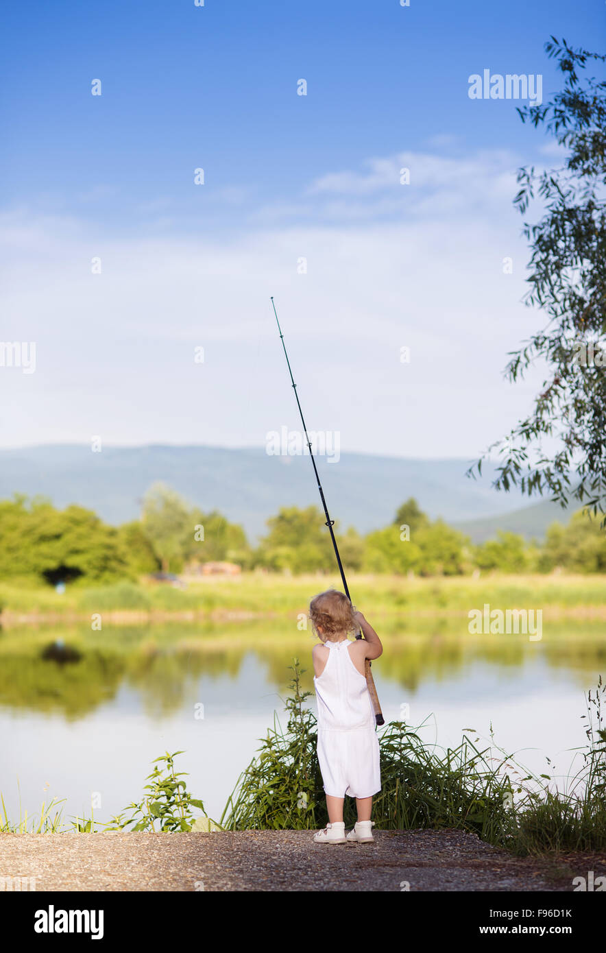 Niedliche kleine Mädchen auf dem See mit Fischen Stockfoto