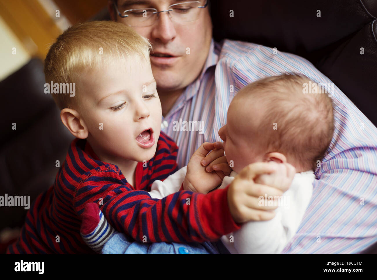 Niedlichen Neugeborenen Baby junge und sein kleiner Bruder mit ihrem Vater zu Hause entspannen Stockfoto