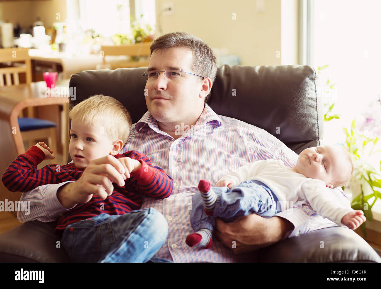 Niedlichen Neugeborenen Baby junge und sein kleiner Bruder mit ihrem Vater zu Hause entspannen Stockfoto