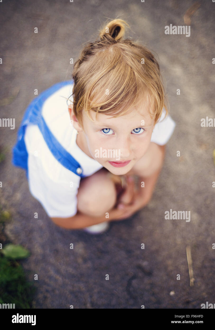 Traurig, kleines Mädchen mit blauen Augen auf der Straße hocken. Stockfoto
