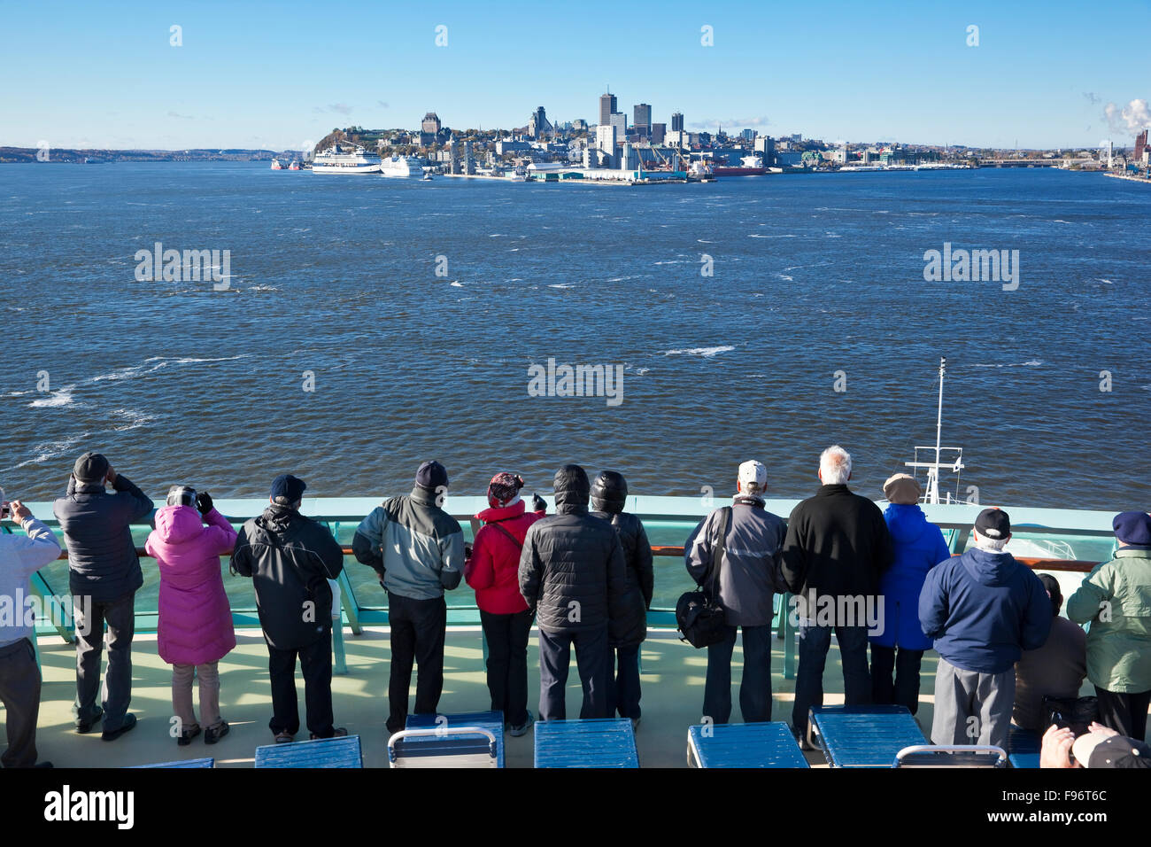 Passagiere auf dem oberen Deck eines Kreuzfahrtschiffes Schiff zusehen, wie ihr Schiff seinen Weg in Richtung Quebec Stadt in der Ferne macht Stockfoto